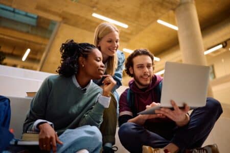 Multiracial,group,of,happy,students,using,laptop,at,the,university.